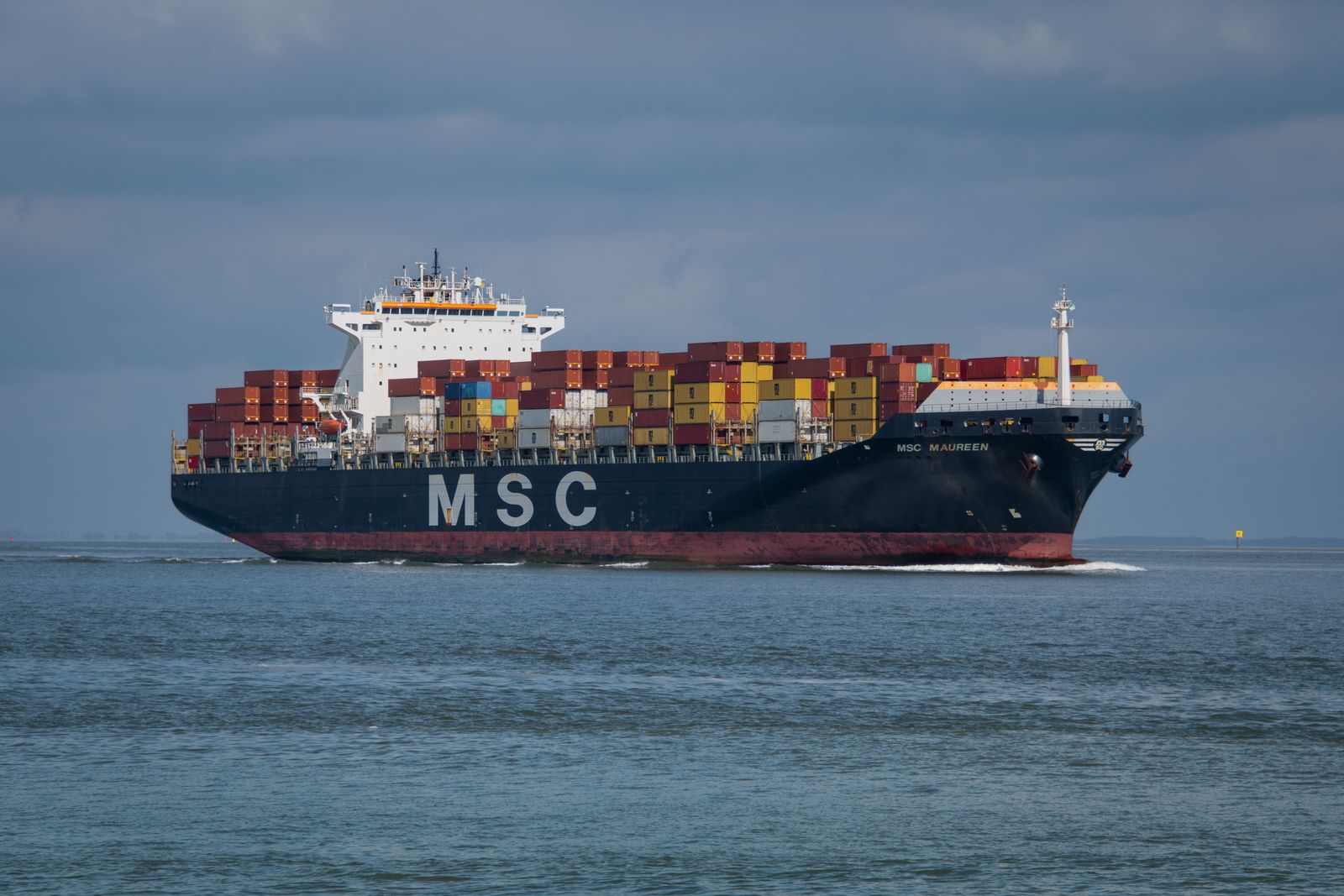 Container ship sailing across a wide blue ocean trade route